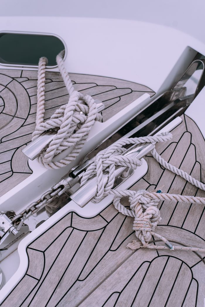 Close-up of nautical ropes organized on a yacht deck with metal fittings and wooden patterns, ideal for marine themes.